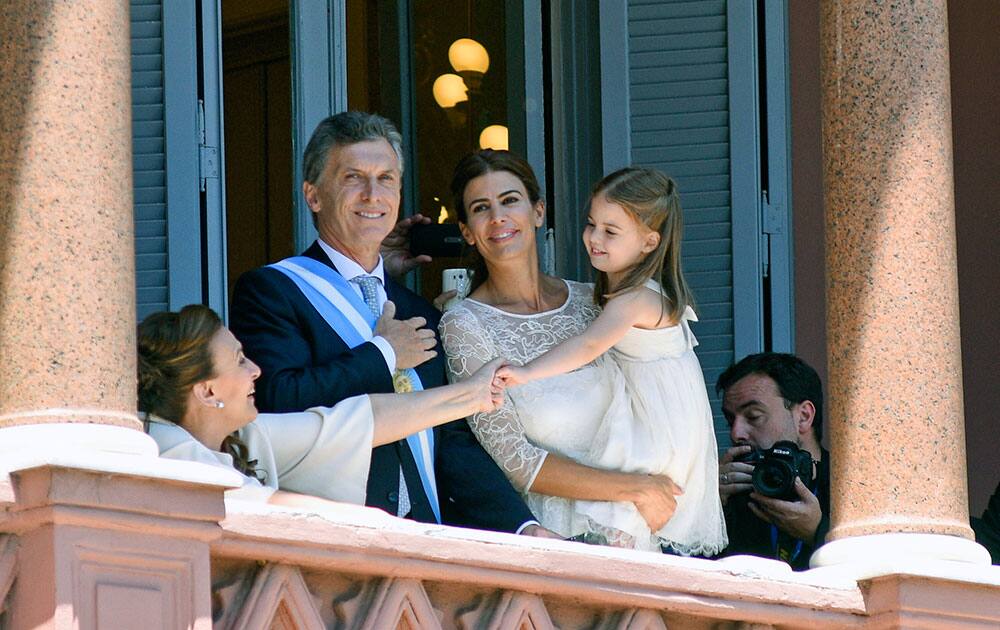 Argentina's President Mauricio Macri, center left, first lady Juliana Awada, center right, holding their daughter Antonia, and Argentina's Vice-President Gabriela Michetti, left, smile to followers from the balcony of the government house in, Buenos Aires, Argentina.