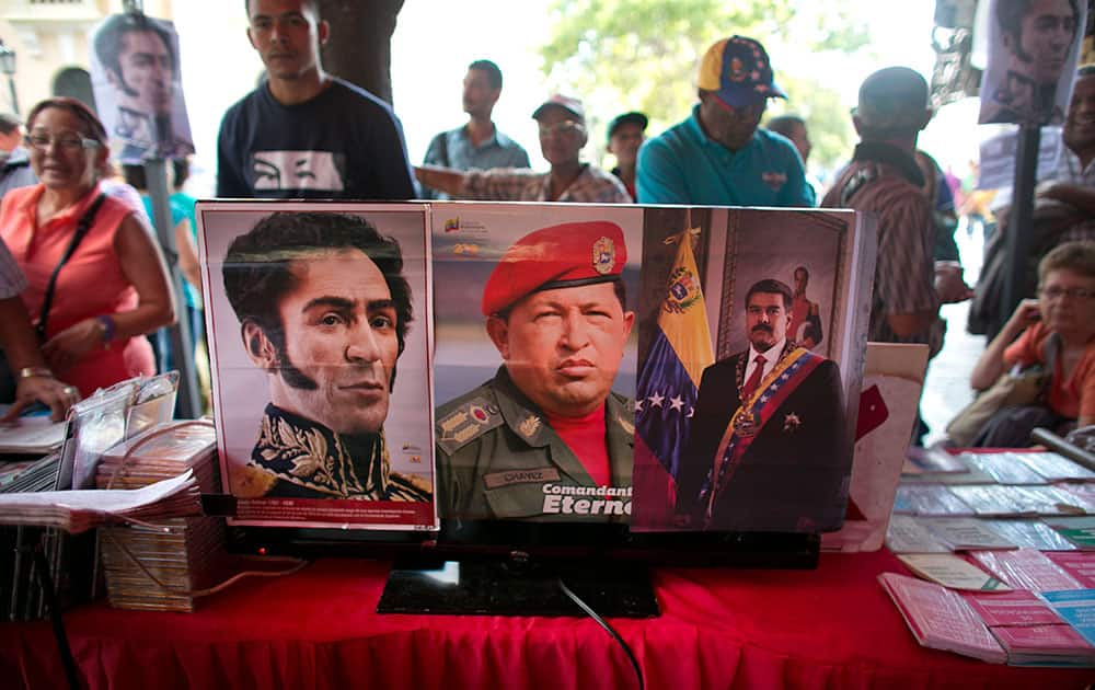 Pictures of Venezuela's independence hero Simon Bolivar, left, Venezuela's late president Hugo Chavez, center, and Venezuela's President Nicolas Maduro are seen pasted on a television screen outside of the National Assembly building during a session in Caracas, Venezuela.