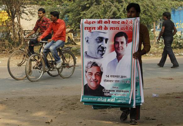 An Indian congress party worker prepares to display banners with photographs of India`s first Prime Minister Jawaharlal Nehru, top left, Congress party leader Rahul Gandhi, right, and Indian Coal Minister Sriprakash Jaiswal, bottom left, on the eve of a public meeting to be addressed by Gandhi at Phulpur.