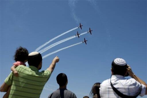 Israelis watch as Israeli air force acrobat planes fly over the Mediterranean sea, part of a flyover, during Israel`s 63rd Independence Day celebrations in Tel Aviv, Israel.