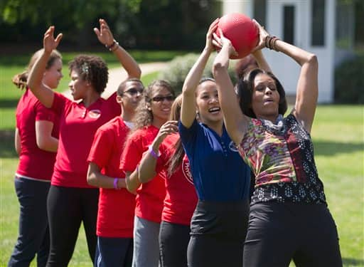 First lady Michelle Obama hands a ball to Olympian skater Michelle Kwan during an event on the South Lawn of the White House in Washington, to promote physical fitness among military families.