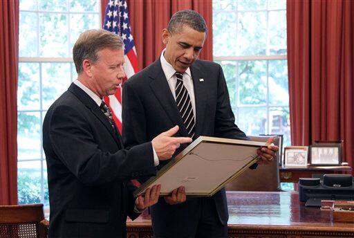 President Barack Obama admires a gift from crew members of the Discovery Space Shuttle, presented to him by commander Steve Lindsey, in the Oval Office of the White House in Washington.