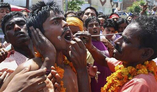 A Hindu devotee of Hindu Goddess Maha Mariamman gets his cheeks pierced with a rod as he prepares to participate in a religious procession in Amritsar.