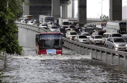 Passenger buses negotiate a flooded portion of a highway at suburban Makati city, east of Manila, in the Philippines.