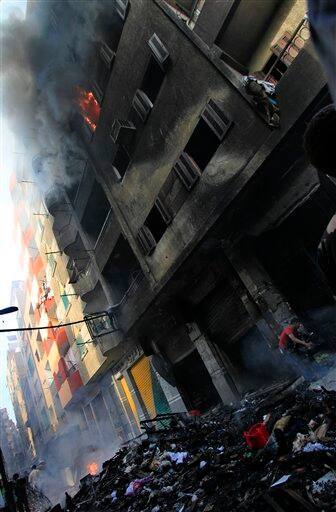 Egyptians gather next to a building belonging to Christians that was set on fire during clashes between Muslims and Christians in the Imbaba neighborhood of Cairo. Two churches in western Cairo were set on fire during clashes between Muslims and Christians triggered by rumors of an interfaith romance that left nine dead in some of the worst sectarian tension since the ouster of the president in a popular uprising.