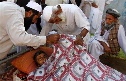 Afghan men remove the blanket to examine the wounds of a man who was allegedly killed in a U.S. operation in Surkhrod district of Nangarhar province east of Kabul, Afghanistan.