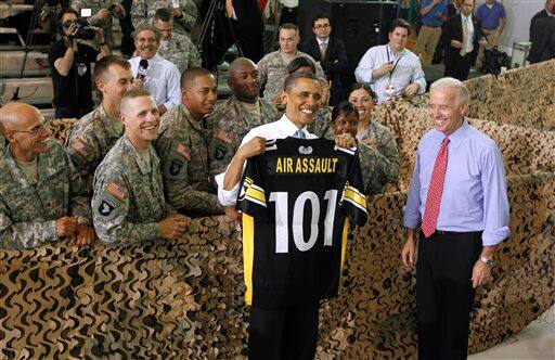 President Barack Obama, accompanied by Vice President Joe Biden, holds up a shirt given to him as he greeted military personnel who have recently returned from Afghanistan.