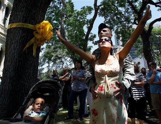 Staff Sgt. Mario Quinn holds the stomach of his pregnant wife, Donna, as they take part in a National Day of Prayer gathering at City Hall in San Antonio.