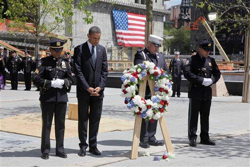 President Barack Obama, accompanied by a New York City Police officer, New York City Firefighter, and Port Authority officer, observers a moment of silence after placing a wreath at the World Trade Center site, in New York.