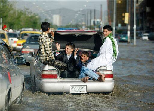 Afghan children enjoy sitting at the back of a car as they avoid getting wet, being carried along a water logged street after a brief spell of rain in Kabul.