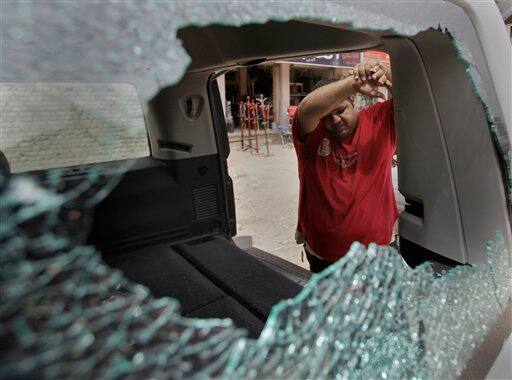 An Iraqi man inspects his damaged car at the site of a roadside bomb attack targeting a police patrol, killing and wounding a few civilians, police said, in central Baghdad.