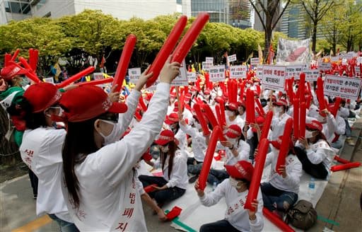 Prostitutes wearing caps and masks to cover their identities raise their balloon sticks during a rally to protest against the enacted anti-prostitution law near the National Assembly in Seoul, South Korea.