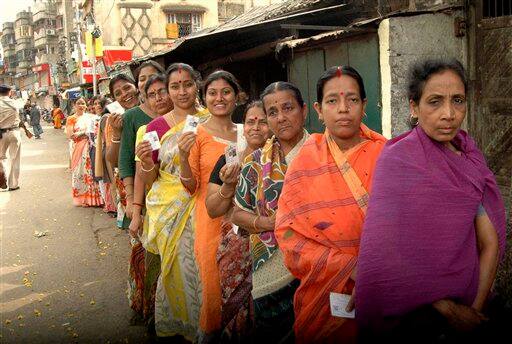 Indian women react to camera as they wait in a queue to cast their votes during the fourth phase of polling for the West Bengal state assembly elections in Howrah district, north of Kolkata.