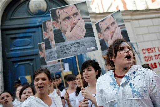 Members of French watchdog organization Reporters Without Borders (RSF) demonstrate with poster showing Syrian President Bashar Assad and reading 