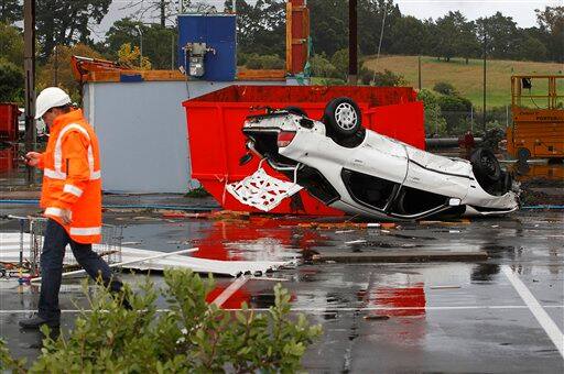 A man walks past a wrecked car at the Albany Mall in suburban Auckland, New Zealand after a tornado ripped through Tuesday, May 3, 2011. The tornado ripped across part of New Zealand`s largest city, upturning cars and sending debris slicing through the air, witnesses and news reports said. At least one person was killed and about 20 injured, a hospital official said.