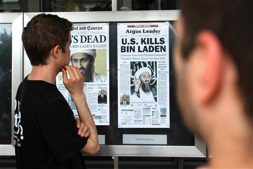 Bryan Byrd, 22, of Washington, left, looks at a display of newspaper front pages at the Newseum in Washington, Monday, May 2, 2011, on the day after Osama bin Laden was killed. 