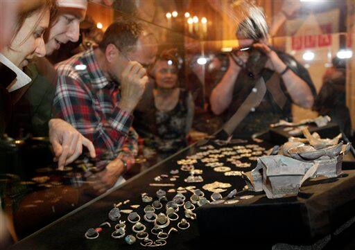 Visitors look at part of a buried treasure exhibited at Austria`s department of national antiquities in Vienna, Austria. A trove of medieval jewelry and other precious objects found by a man working in his backyard includes pieces made for a royal court and may be worth as much as 100,000 euros ($150,000) government experts said Monday.