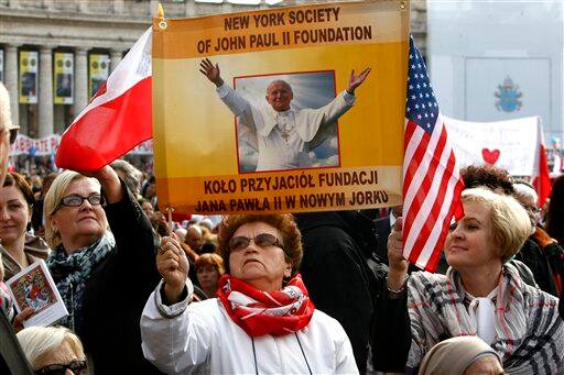 Faithful hold a banner as they wait for a solemn celebration led by Pope Benedict XVI where late Pope John Paul II will be beatified, in St. Peter`s Square at the Vatican, Sunday, May 1, 2011, in the fastest beatification in modern times.