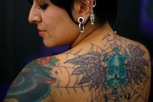 A tattooed woman poses for pictures during the 5th annual Tattoo Neza Expo in Nezahualcoyotl, Mexico.