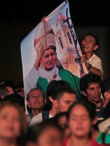 A man holds up a banner with an image of late Pope John Paul II during a vigil honoring him in Granada, Nicaragua.