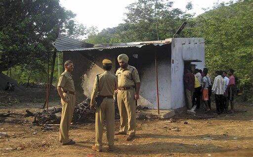 Local police officers stand near a burnt room as villagers look inside from the door in Bandaguda village, about 250 miles from Bhubaneswar.