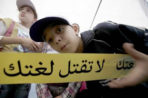 A Lebanese child poses behind a ribbon that reads