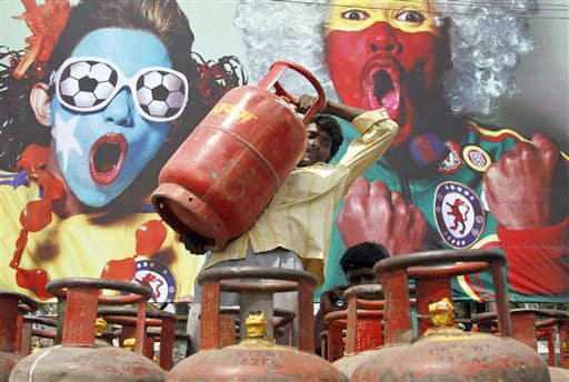 An Indian laborer unloads a cooking gas cylinder from a trolley for distribution in Allahabad, India, Saturday, June 26, 2010. India`s government decided to hike fuel prices Friday, a politically contentious move analysts say could save the state $5.2 billion but exacerbate high inflation by as much as a percentage point.