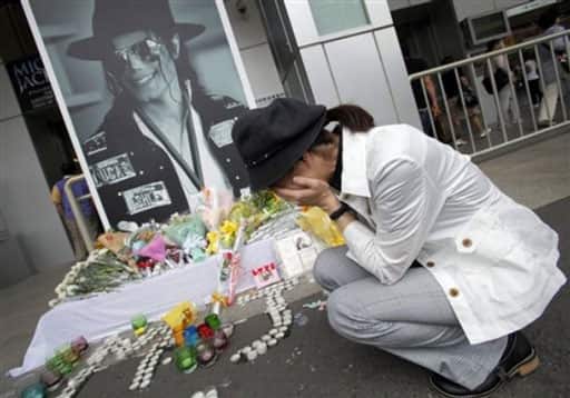 A woman cries in front of a portrait of late Michael Jackson displayed at a makeshift memorial place on his first death anniversary in Tokyo, Japan, Saturday, June 26, 2010.
