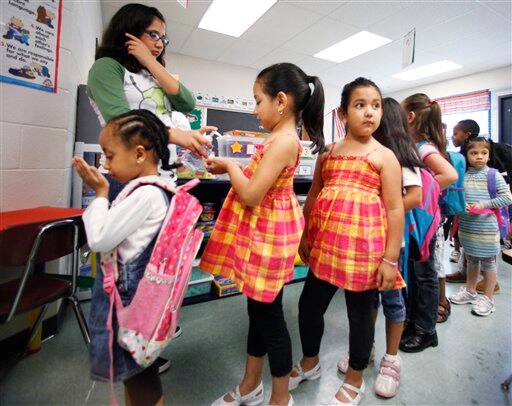 This photo taken Wednesday, July 29, 2009 shows would be Kindergatens given hand sanitizer before going to lunch at a summer school program in Montgomery County`s Brookhaven Elementary School, in Rockville, Md.