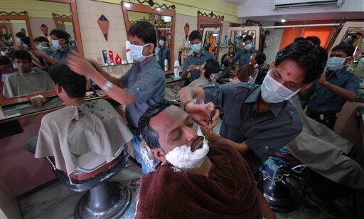 Workers at a salon wear masks as a preventive measure against swine flu in Ahmadabad, India, Wednesday, Aug. 12, 2009. Authorities ordered the closure of all schools and movie theaters in Mumbai on Wednesday, as the number of swine flu fatalities in the country rose to 15, officials and news reports said.