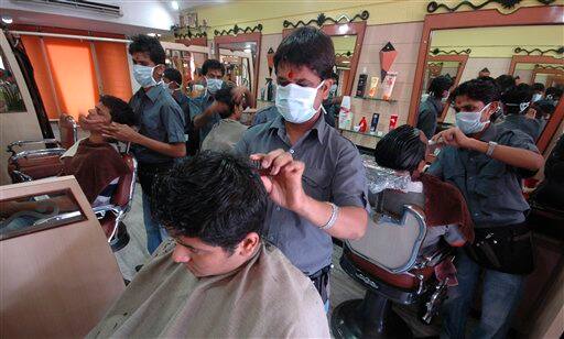 Workers at a salon wear masks as a preventive measure against swine flu in Ahmadabad, India, Wednesday, Aug. 12, 2009. Authorities ordered the closure of all schools and movie theaters in Mumbai on Wednesday, as the number of swine flu fatalities in the country rose to 15, officials and news reports said.