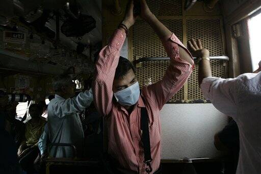 A commuter on a local train wears a surgical mask as a preventive measure against swine flu, in Mumbai, India, Wednesday, Aug. 12, 2009. Authorities ordered the closure of all schools and movie theaters in Mumbai on Wednesday, as the number of swine flu fatalities in the country rose to 15, officials and news reports said.