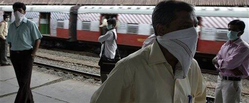 Local train commuters cover their faces as a preventive measure against swine flu, in Mumbai, India, Wednesday, Aug. 12, 2009. Authorities ordered the closure of all schools and movie theaters in Mumbai on Wednesday, as the number of swine flu fatalities in the country rose to 15, officials and news reports said.