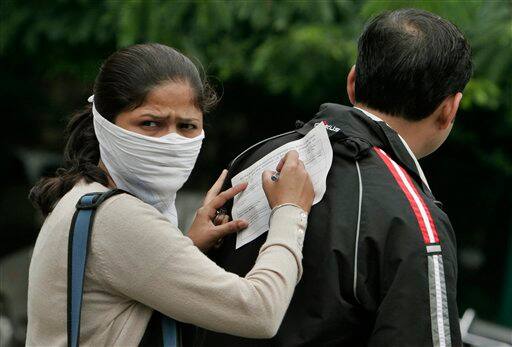 A woman writes her personal details on a form as she waits to get examined for swine flu virus at a government hospital in Bangalore, India, Tuesday, Aug. 11, 2009. The countrywide death toll due to swine flu related virus has gone up to 10, a news agency reported.