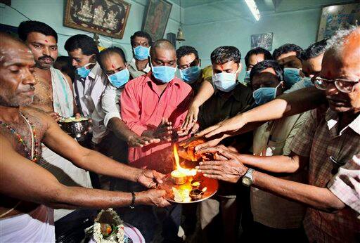 People wearing masks worship Lord Shiva to prevent them from swine flu virus, in Bangalore, India, Tuesday, Aug. 11, 2009.