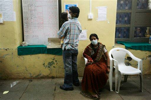 A couple wearing protective masks waits for their child suffering from fever to get tested for the swine flu virus inside Naidu Hospital in Pune, India, Tuesday, Aug. 11, 2009. The country-wide death toll due to swine flu related virus has gone up to 10, a news agency reported.