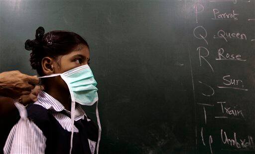 A teacher helps a student to put on a mask, at a school in Mumbai, India, Monday, Aug. 10, 2009. A regional party, the Shiv Sena distributed masks in schools as a preventive measure against swine flu. According to media reports, two more people infected with swine flu have died, raising the country`s death toll from the virus to six.