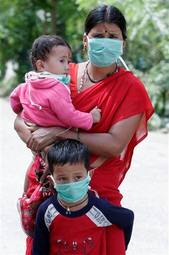 A woman waits with her children to get themselves examined at a swine flu examination center at a government hospital in Bangalore, India, Monday, Aug. 10, 2009. According to media reports, two more people infected with swine flu have died, raising the country`s death toll from the virus to six.