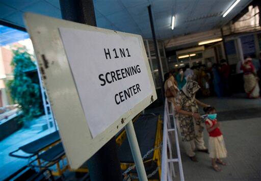 A mother helps her daughter wear a respiratory mask outside a H1N1 Swine flu examination center at a government hospital in New Delhi, India, Sunday, Aug. 9, 2009. Media reports say three more people infected with swine flu have died in India, raising the country`s death toll related to the virus to four.