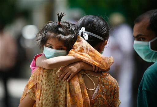 A family wears respiratory masks outside a H1N1 Swine flu examination center at a government hospital in New Delhi, India, Sunday, Aug. 9, 2009. Media reports say three more people infected with swine flu have died in India, raising the country`s death toll related to the virus to four.