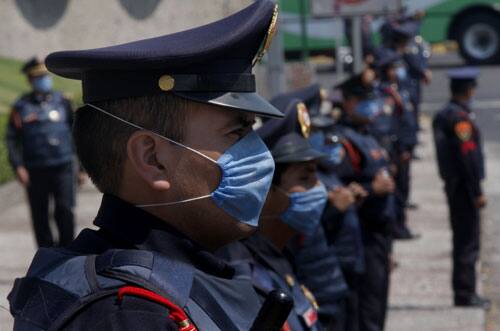 Police officers wearing surgical masks stand outside Mexico`s National Autonomous University soccer stadium, which was closed to the public, before a game between Pumas and Chivas in Mexico City, Sunday, April 26, 2009.