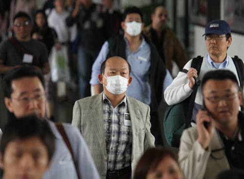 Airline passengers, some wearing face masks, arrive at the Ninoy Aquino International Airport being closely monitored for flu-like symptoms Monday April 27, 2009