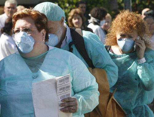 A medical staff member wearing a mask, left leads two patients who are undergoing tests for the swine flu virus at 