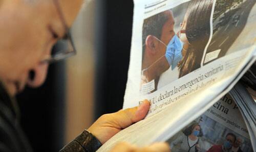 A man reads a newspaper article about the swine flu scare, at the airport in Barcelona, Spain, Monday, April 27, 2009.