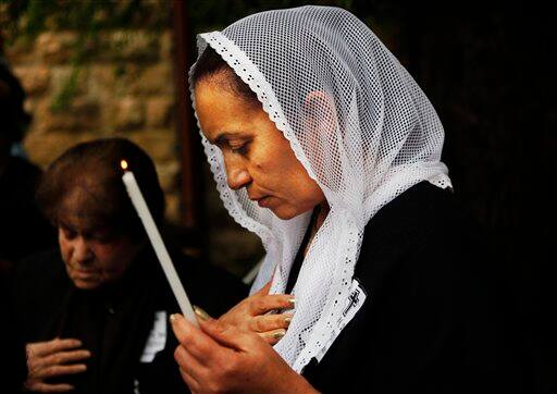 An Armenian woman holds a candle during a prayer marking the 94th anniversary of the mass killing of the Armenian people, at a monument next to St. James Cathedral in the Armenian Quarter of Jerusalem`s Old City