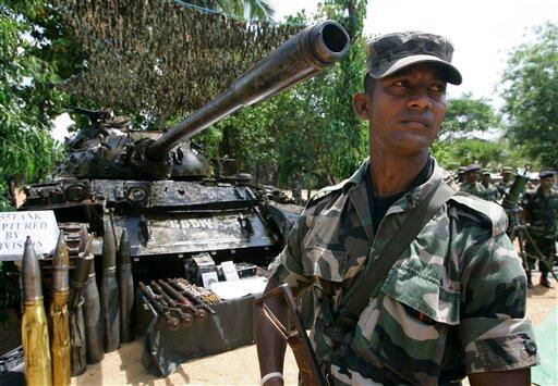 A Sri Lankan soldier stands guard next to a tank which was captured from Tamil Tiger rebels at Killinochchi, about 230 kilometers (143 miles) northeast of Colombo