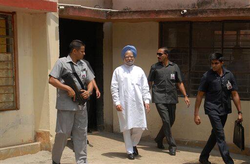 Indian Prime Minister Manmohan Singh, in white, comes out of a polling booth after casting his vote in Gauhati, India