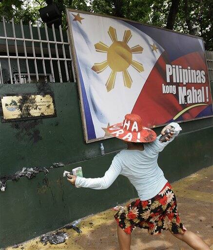 An activist throws mud on the gates of the Department of Environment and Natural Resources headquarters during a protest in suburban Quezon City, North of Manila, Philippines. Environmental activists commemorated Earth Day 