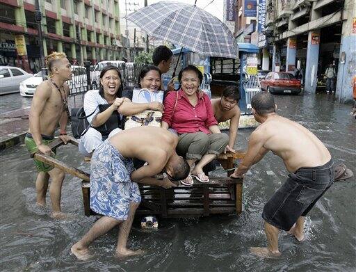 Filipino women enjoy a ride on a cart to keep them dry from flood waters in Manila, Philippines Smoke-belching passenger vehicles which cause pollution and trash-clogged drainage pipes that contribute to flooding remain a problem as the nation observes Earth Day .