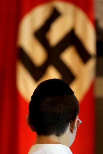 An ultra-Orthodox Jewish boy stands in front of a Nazi flag on display at the Yad Vashem Holocaust museum in Jerusalem. Frenetic Israel came to a standstill for two mournful minutes on Tuesday as air-raid sirens pierced the air in remembrance of the 6 million Jews who perished in the Nazi Holocaust.